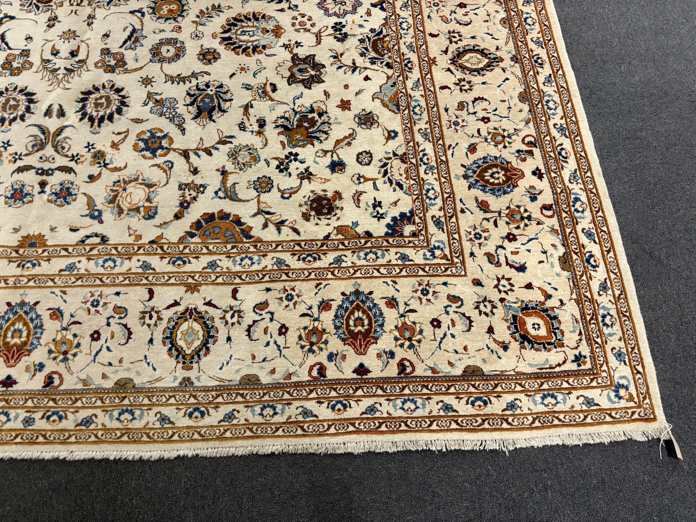 A Kashan ivory ground carpet, central field of foliate motifs, multi bordered, 400 x 308cm, Please note this lot attracts an additional import tax of 5% on the hammer price